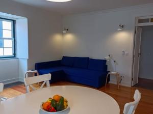 - un salon avec un canapé bleu et une table avec un bol de fruits dans l'établissement Apartamentos Ázera - Laura Ázera, à Praia da Vitória
