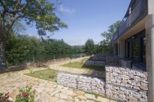 a building with a stone wall next to a river at Hotel du Lac & Restaurant Foix in Foix