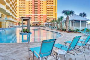 una piscina con sillas azules y un edificio en Calypso Resort Tower 3 en Panama City Beach