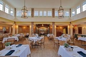 a restaurant with white tables and chairs and windows at Briars Resort and Spa in Georgina
