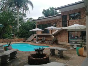 a house with a swimming pool with benches and umbrellas at Hidden Inn in Pietermaritzburg