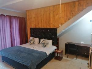 a bedroom with a bed and a desk in it at Hidden Inn in Pietermaritzburg