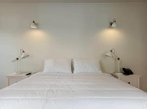 a white bed with two lamps on top of it at Apartamentos Ázera - Isolino Ázera in Praia da Vitória