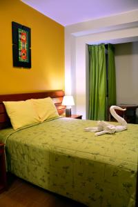a bedroom with a bed with a green bedspread at Hotel Sol del Sur in Nazca
