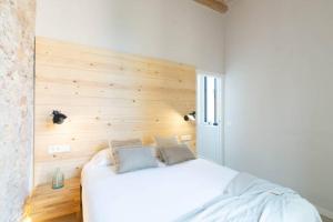 1 dormitorio con cama blanca y pared de madera en Domina Boutique Apartment, en Girona