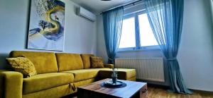 a living room with a yellow couch and a table at Apartman VARENICA in Doboj