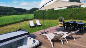 a grill with a table and chairs and an umbrella at Villa ADurbuy avec Jacuzzi in Durbuy