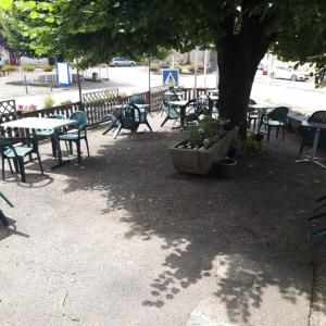 a group of tables and chairs under a tree at Chambres d'hotes Condat in Condat-sur-Ganaveix