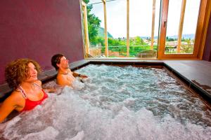 Ein Mann und eine Frau sitzen in einem Whirlpool in der Unterkunft Hotel Goldener Stern in Kaltern