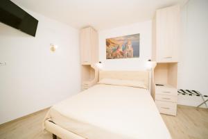 a white bedroom with a bed and a painting on the wall at Lemons & Sun Apartment in Scala