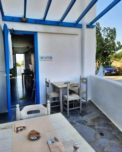 un patio con mesa, sillas y una pared blanca en Studio Elisabeth, en Agios Ioannis