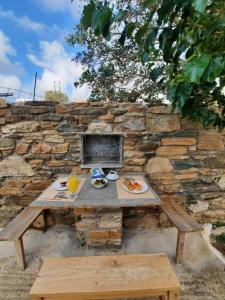 una mesa de picnic con comida y una pared de piedra en Studio Elisabeth, en Agios Ioannis