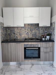 a kitchen with white cabinets and a stove top oven at Kalos Casa Vacanza in Salice Salentino +9 photos