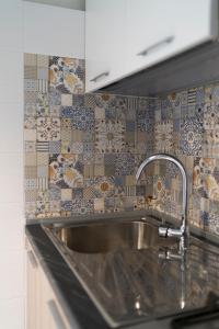 a kitchen with a sink and a tile wall at Kalos Casa Vacanza in Salice Salentino