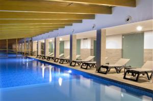 uma piscina num edifcio com cadeiras e uma piscina em Luna Chalets da Montanha - Serra da Estrela na Covilh