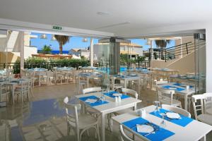a restaurant with white tables and white chairs at Eurohotel Katrin Suites in Stalida