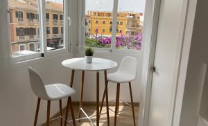 una pequeña mesa blanca y sillas en una habitación con ventanas en Mi Villa Apartamentos Dénia Centro, en Denia