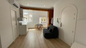 a living room with a black couch and a kitchen at Mi Villa Apartamentos Dénia Centro in Denia