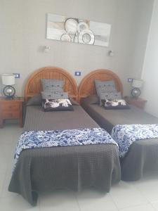 プエルト・デル・カルメンにあるApartmento Juana 2のベッド2台(壁に皿を敷いた部屋)
