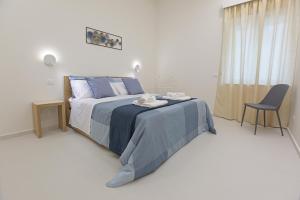 una camera con un letto con una coperta blu e una sedia di Casa Timone a San Leone