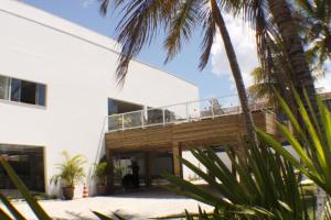 a white building with a deck and palm trees at Hotel Abrolhos in Nova Viçosa