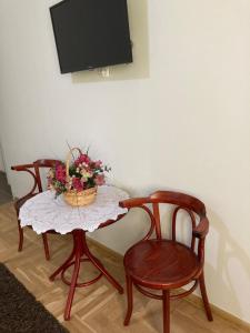 a table with a basket of flowers and two chairs at Salvus Panzió in Bükkszék