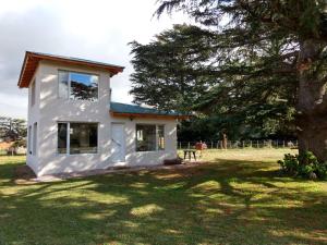une maison blanche avec un arbre dans la cour dans l'établissement Maika La Peke, à Sierra de la Ventana