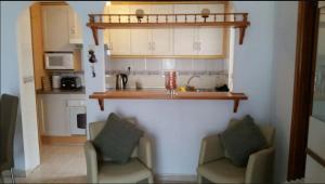 a kitchen with two chairs and a sink and a counter at Inviting 2-Bed Apartment 5 minutes to the beach in Punta Prima