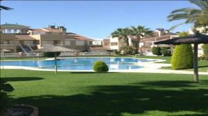 a swimming pool with umbrellas in a yard at Inviting 2-Bed Apartment 5 minutes to the beach in Punta Prima