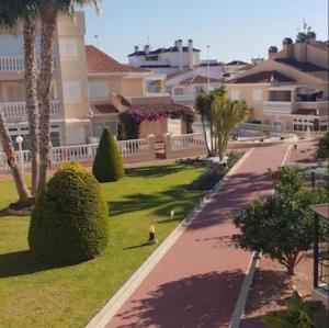 a park with palm trees and bushes and buildings at Inviting 2-Bed Apartment 5 minutes to the beach in Punta Prima
