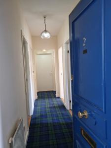 einen Flur mit blauer Tür und blauem Boden in der Unterkunft Carnarvon Street City Centre Apartment in Glasgow