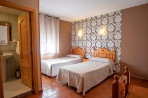 a bedroom with two beds and a bathroom with a sink at Hotel La Braña in San Isidro