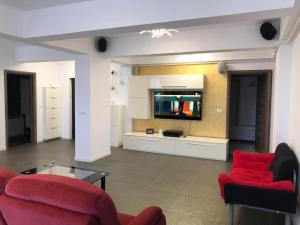 a living room with two red chairs and a tv at Silvester Residence in Năvodari