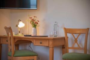 un escritorio de madera con 2 sillas y un jarrón de flores. en Hotel & Pension "Zum Birnthaler", en Kallmünz