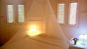 a bedroom with a white bed with a mosquito net at Las Puertas del Paraíso in Río San Juan