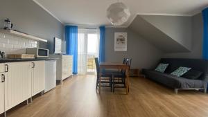 un soggiorno con un divano, un tavolo e una cucina di Sunrise Apartamenty a Łeba