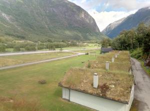 a building with grass on the roof with mountains in the background at Hjelledalen Hyttesenter in Hjelle
