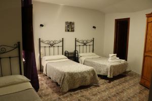 a bedroom with two beds with white sheets and a table at Hostal La Alberca in La Alberca