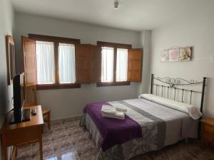 1 dormitorio con 1 cama, TV y ventanas en Hostal La Alberca, en La Alberca