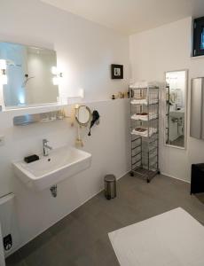 baño con lavabo, espejo y estante en Mit Aufzug in die Ferienwohnung "Zum Ritter" und mit in der Nähe von Köln Stil übernachten en Pulheim