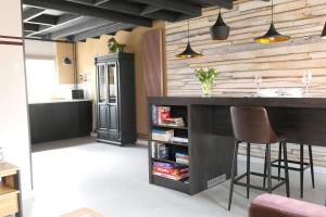 een keuken met een bar met stoelen en een boekenplank bij Appartement ' Het Zilte'. in Yerseke