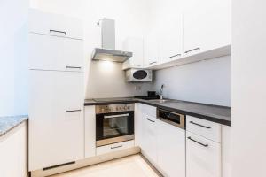 a white kitchen with white cabinets and appliances at Family apartment next to Danube river in Vienna