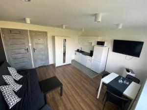 salon z kanapą i stołem oraz kuchnia w obiekcie Apartamenty Czapla w mieście Mikołajki