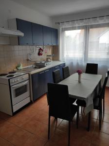 cocina con mesa, fogones, mesa y sillas en Apartman Domi en Slunj