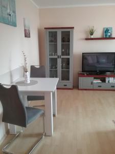 ein Wohnzimmer mit einem weißen Tisch und einem TV in der Unterkunft Ferienwohnung Paula, Kluis in Gagern