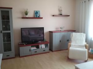 a living room with a television and a white chair at Ferienwohnung Paula, Kluis in Gagern