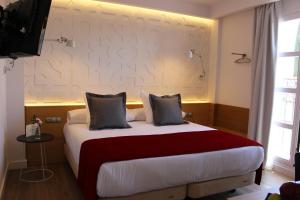 a bedroom with a large bed with a red blanket at Hotel Boutique Caireles in C&oacute;rdoba