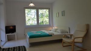 a bedroom with a bed and a chair and a window at W Chmurach in Karpacz