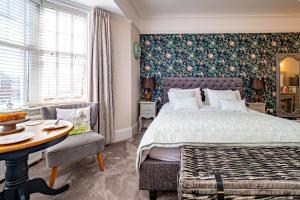a bedroom with a large bed and a table and chairs at Merlstead House in Hornsea