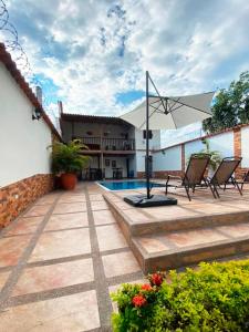 a patio with chairs and an umbrella and a pool at Hotel Boutique Colonial Cartago in Cartago